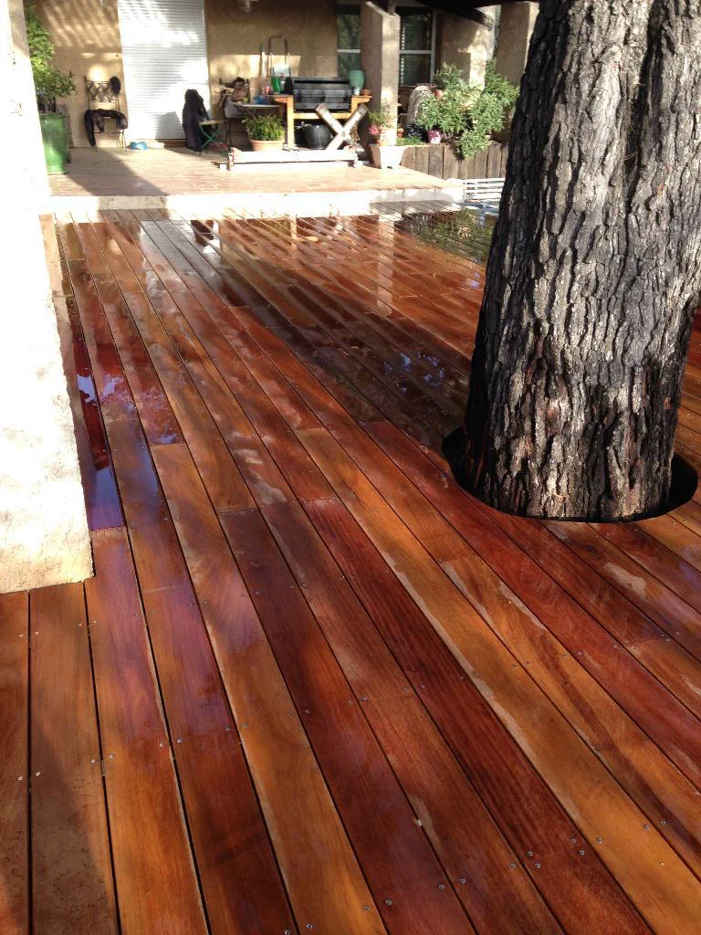 Terrasse extérieure habillée de lames de bois autour d’un arbre
